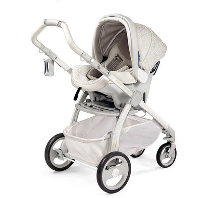 Light grey carrycot stroller with a raised canopy, white frame and storage basket, shown from the side.