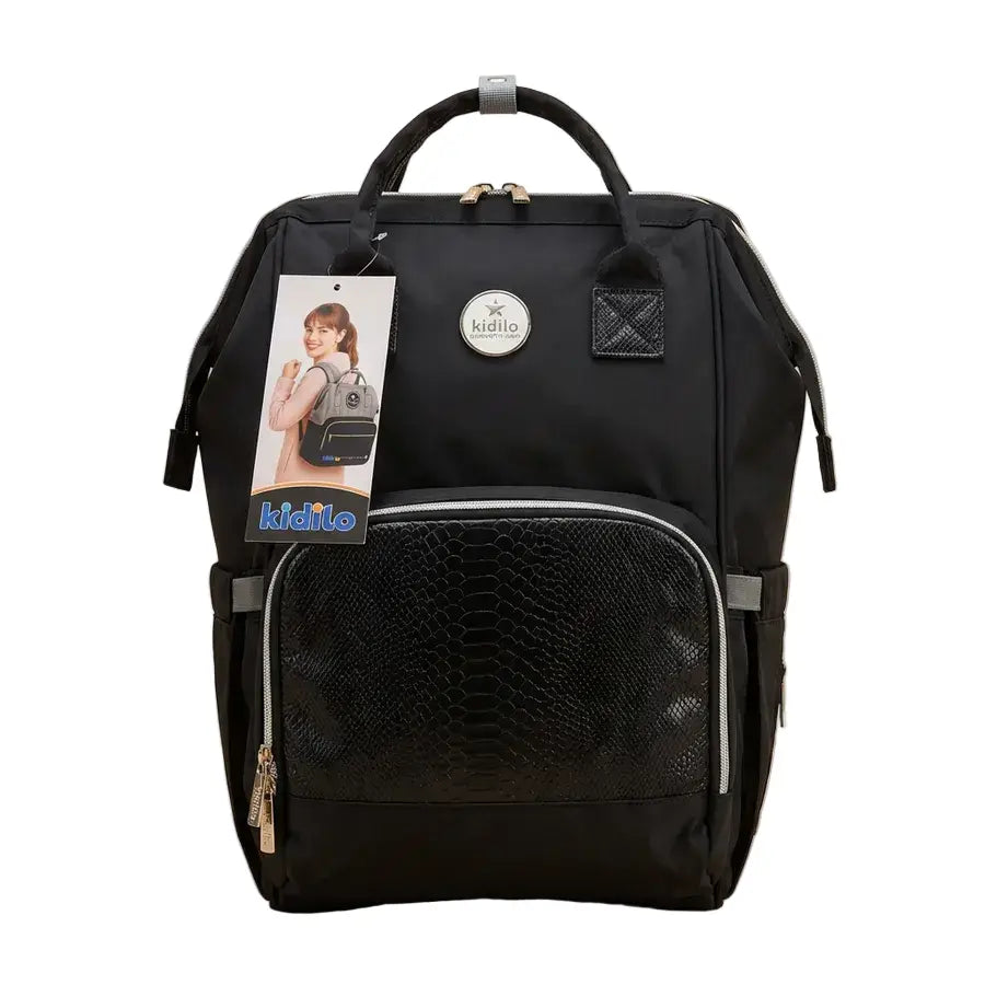 Kidilo black diaper backpack front view with textured zip pocket, round logo patch, top handles and product tag.