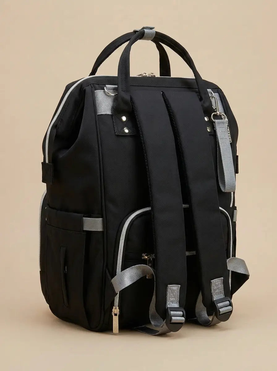Kidilo black diaper backpack rear angled view showing padded shoulder straps, grey loops and zipped back pocket.