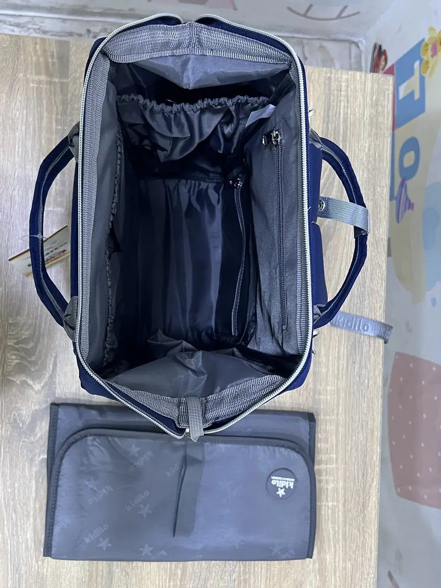 Kidilo blue diaper backpack top view showing open grey-lined compartment and a grey changing mat beside it.