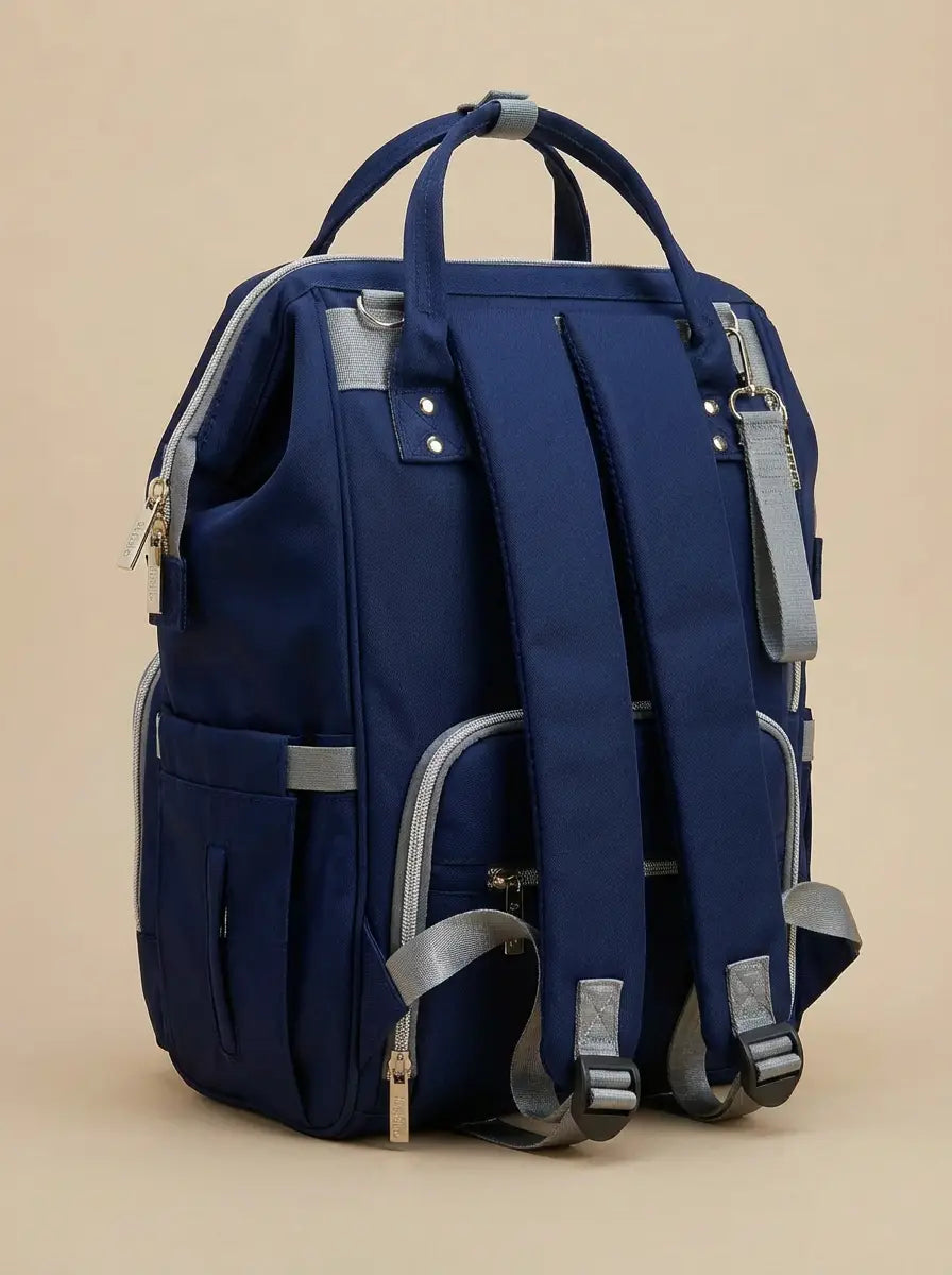 Kidilo blue diaper backpack rear angled view showing padded straps, grey buckles, side pocket and back zip pocket.