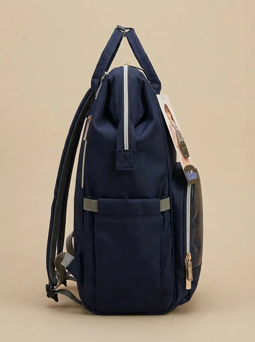 Kidilo blue diaper backpack in side profile against beige, showing tall pocket, light zipper and grey trim.