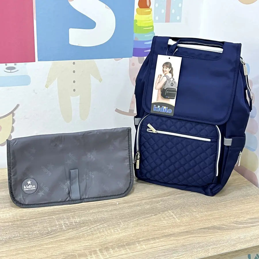 Kidilo X003: blue bag and grey changing mat photographed on a wooden table.