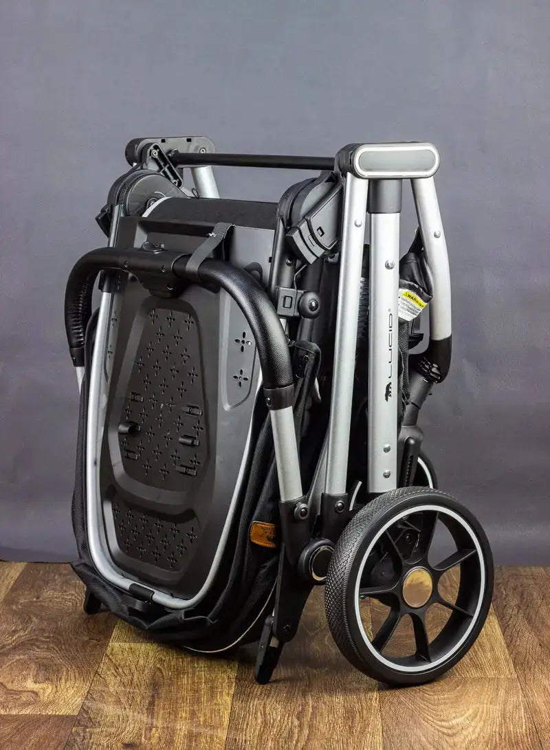 Lucid VIOLA LC8: Folded black stroller standing upright beside a wall