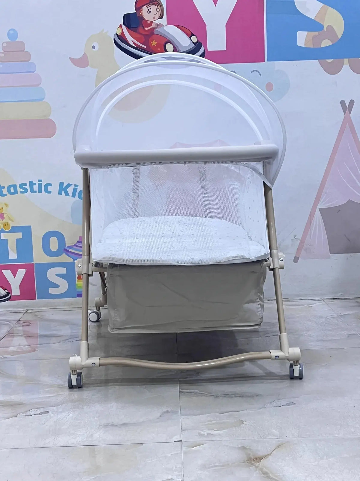 Nivorra NB-3F: beige bassinet end view on tiled floor with net and lower basket.