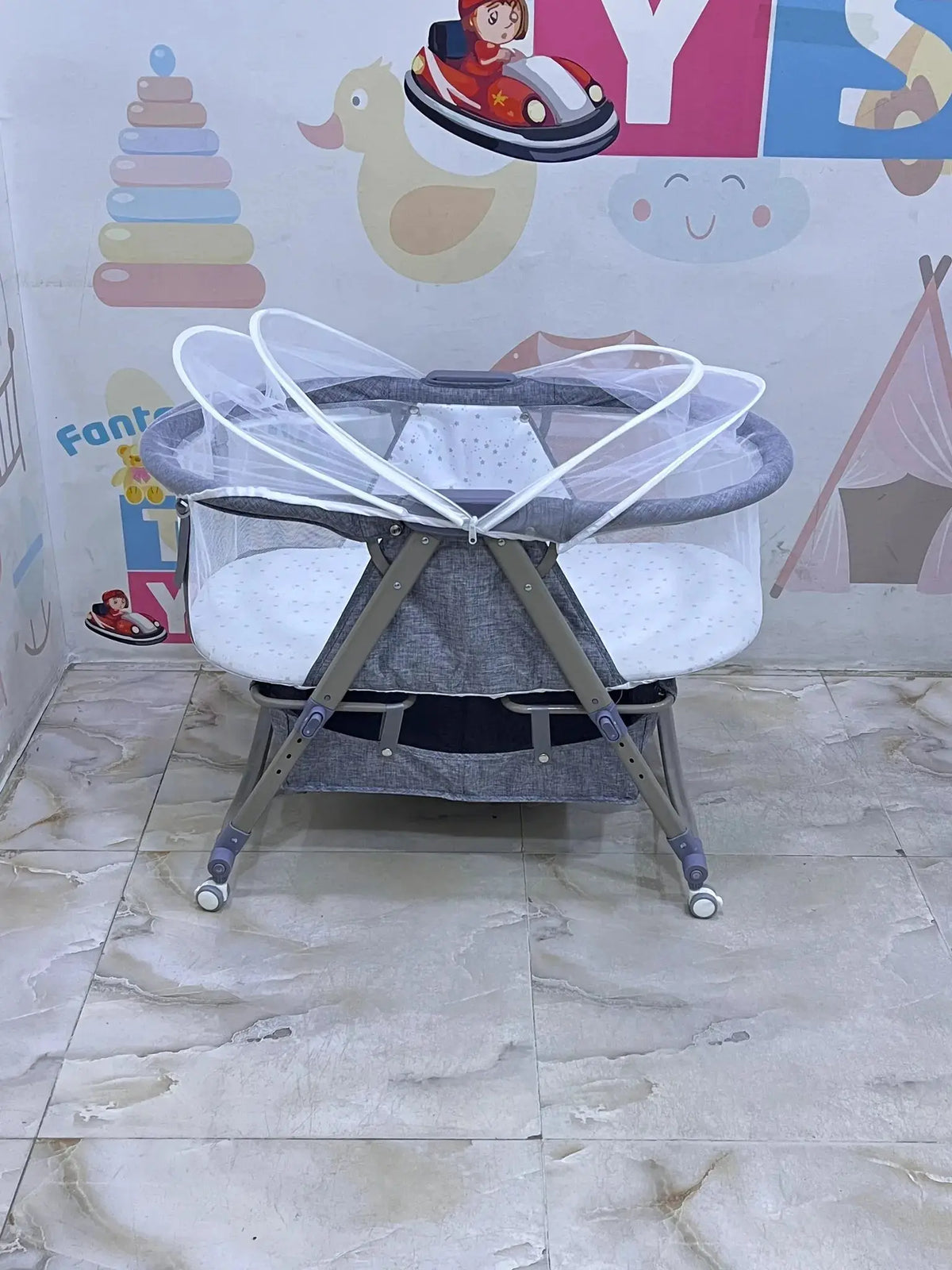 Nivorra NB-3F: grey bassinet with white net partly folded back above mesh sides.