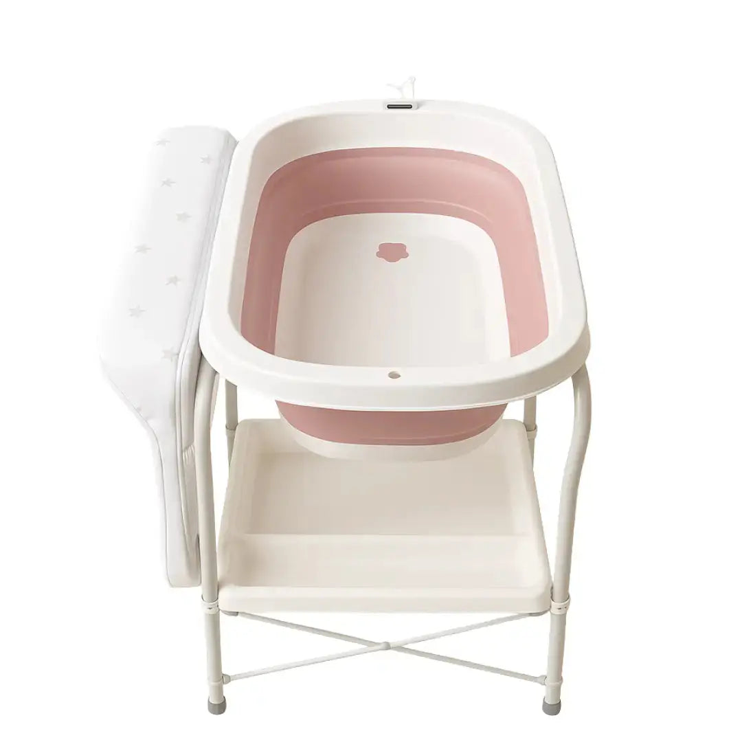 QC6606: Pink baby bath on white stand with raised side changing surface and shelf below.