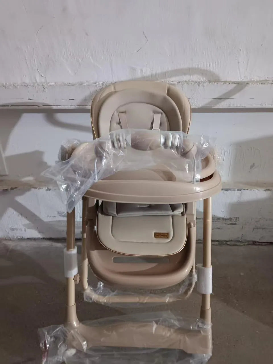 Umbrella X17 Pro: beige high chair front view with packaging around tray and frame.
